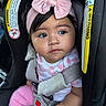 Madison is registered to the contest to win money with this photo: baby, child, car_seat, pink_bow, headband, safety_harness, clothing, infant, cute, indoors, car_interior, person, face, portrait, young_child, seated, looking_away, soft_lighting, close_up, adorable