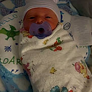 Leland joined the competition — help win amazing prizes! newborn, baby, pacifier, blanket, swaddle, hat, face, infant, bed, sleeping, cute, child, dinosaur_print, pattern, floral, comfort, rest, soft, indoors, portrait