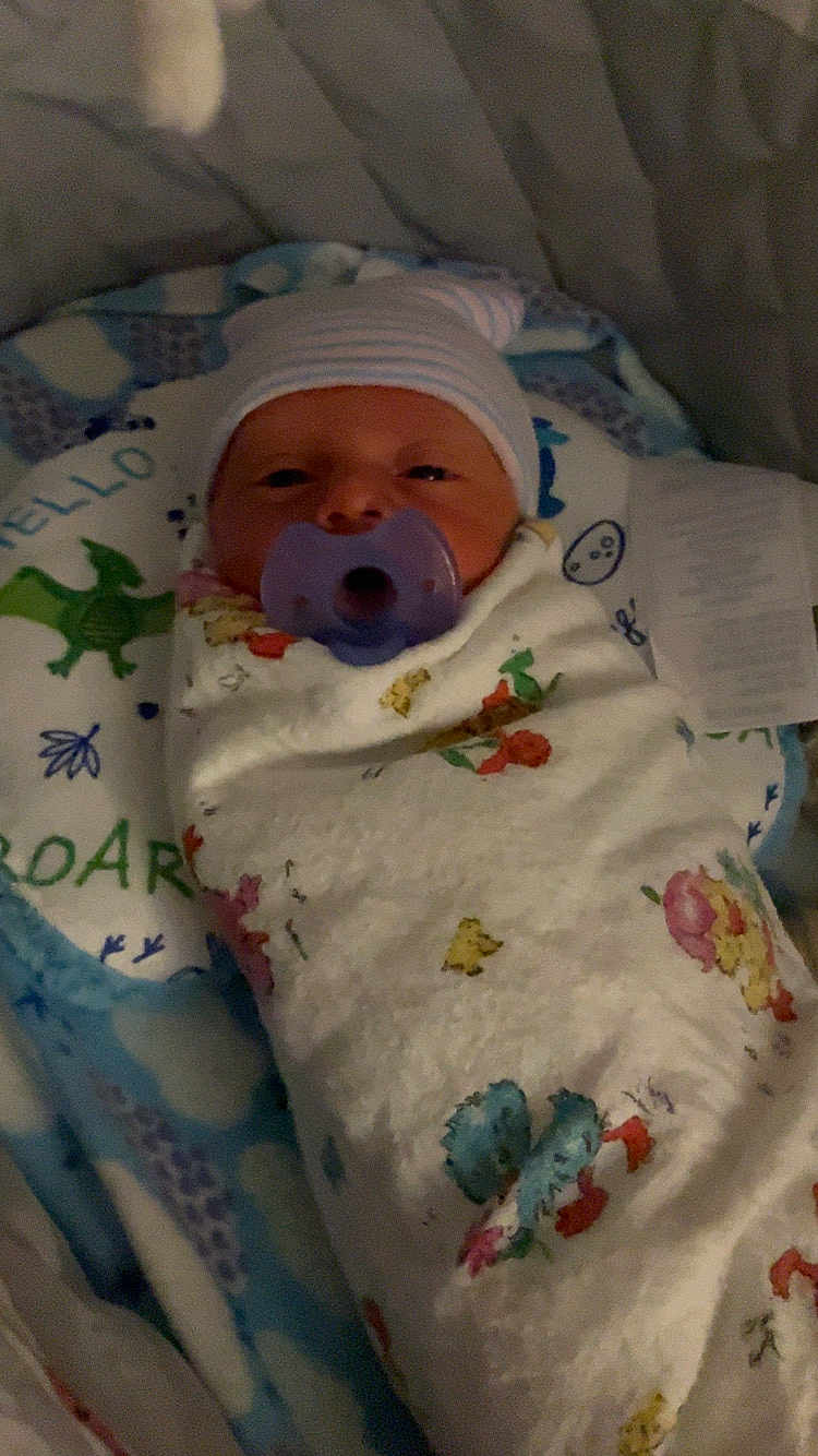 Leland joined the competition — help win amazing prizes! newborn, baby, pacifier, blanket, swaddle, hat, face, infant, bed, sleeping, cute, child, dinosaur_print, pattern, floral, comfort, rest, soft, indoors, portrait