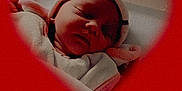 Saphira participe au concours pour gagner de l'argent avec cette photo : baby, newborn, sleeping, blanket, hat, heart_shape, red_background, portrait, infant, closeup, soft_light, cozy, bed, peaceful, cute, child, wrapped, indoors, face, resting