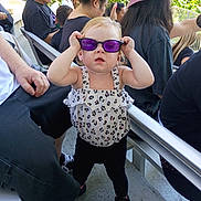 Winter joined the competition — help win amazing prizes! child, toddler, sunglasses, purple_glasses, standing, outdoor, sunlight, crowd, adults, seated_people, portrait, fashion, dress, leopard_print, hair_bow, playful, funny, railings, chairs, park