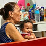 Lanayah-La'Raa joined the competition — help win amazing prizes! elderly_woman, baby, child, smiling, curly_hair, indoor, mirror, bottle, furniture, person, holding, happy, seated, face, portrait, casual_clothing, background, table, red, blue