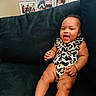 A Marie joined the competition — help win amazing prizes! baby, smiling, infant, leopard_print, onesie, couch, sofa, happy, child, indoor, portrait, family_photos, frame, home, furniture, person, skin, legs, hand, seated