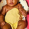 A Marie is registered to the contest to win money with this photo: baby, infant, bathtub, yellow_towel, pink_bathtub, cushion, star_pattern, curious, skin, child, sitting, water, indoors, cute, chubby, expression, head, legs, arms, bath_time