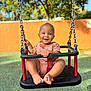 Xavier a rejoint le concours — aidez-le/la à gagner de superbes lots ! baby, child, swing, playground, smiling, outdoor, sunny, trees, orange_wall, green_ground, feet, hands, chains, seat, happy, person, infant, casual_clothing, park, daytime