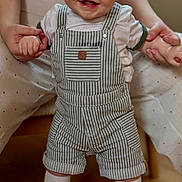 Eden participe au concours pour gagner de l'argent avec cette photo : baby, child, smiling, overalls, striped_overalls, green_sneakers, socks, hands, adult_hands, indoor, wood_floor, portrait, happy, cute, short_hair, playful, fashion, seated, expression, eyes