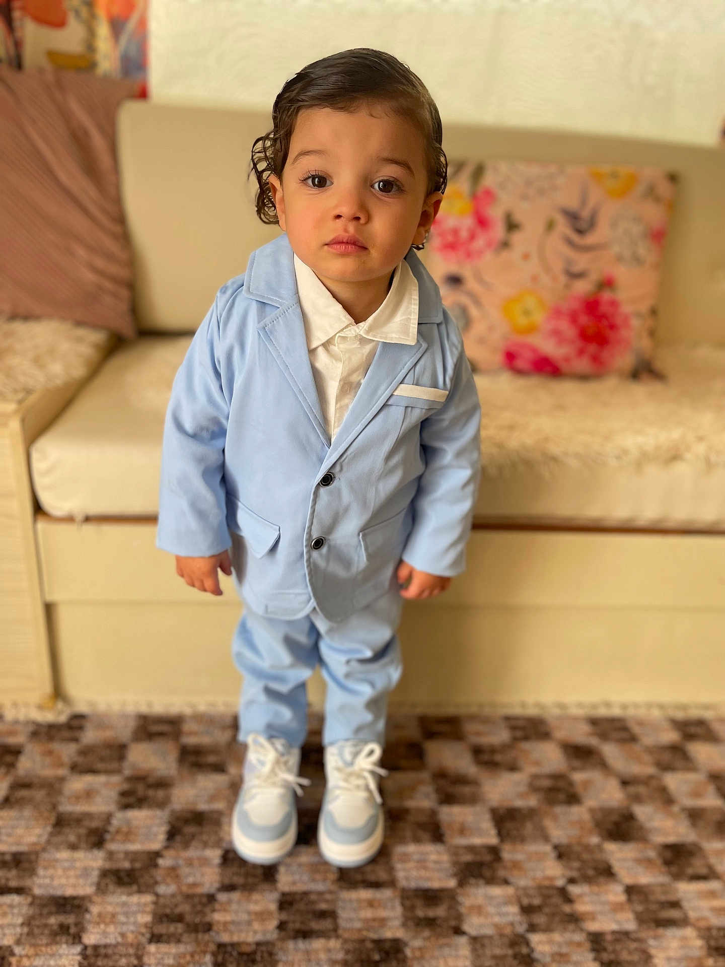 Chris a rejoint le concours — aidez-le/la à gagner de superbes lots ! toddler, child, boy, suit, blue_suit, white_shirt, sneakers, carpet, couch, pillow, indoor, portrait, standing, serious, cute, fashion, young_child, person, home, furniture