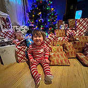 Novs joined the competition — help win amazing prizes! toddler, child, christmas_tree, presents, gift_wrapping, holiday, indoors, floor, smile, festive_lights, wooden_floor, red_stripes, pajamas, happy, holiday_decor, wrapped_gifts, celebration, festive, home, cute