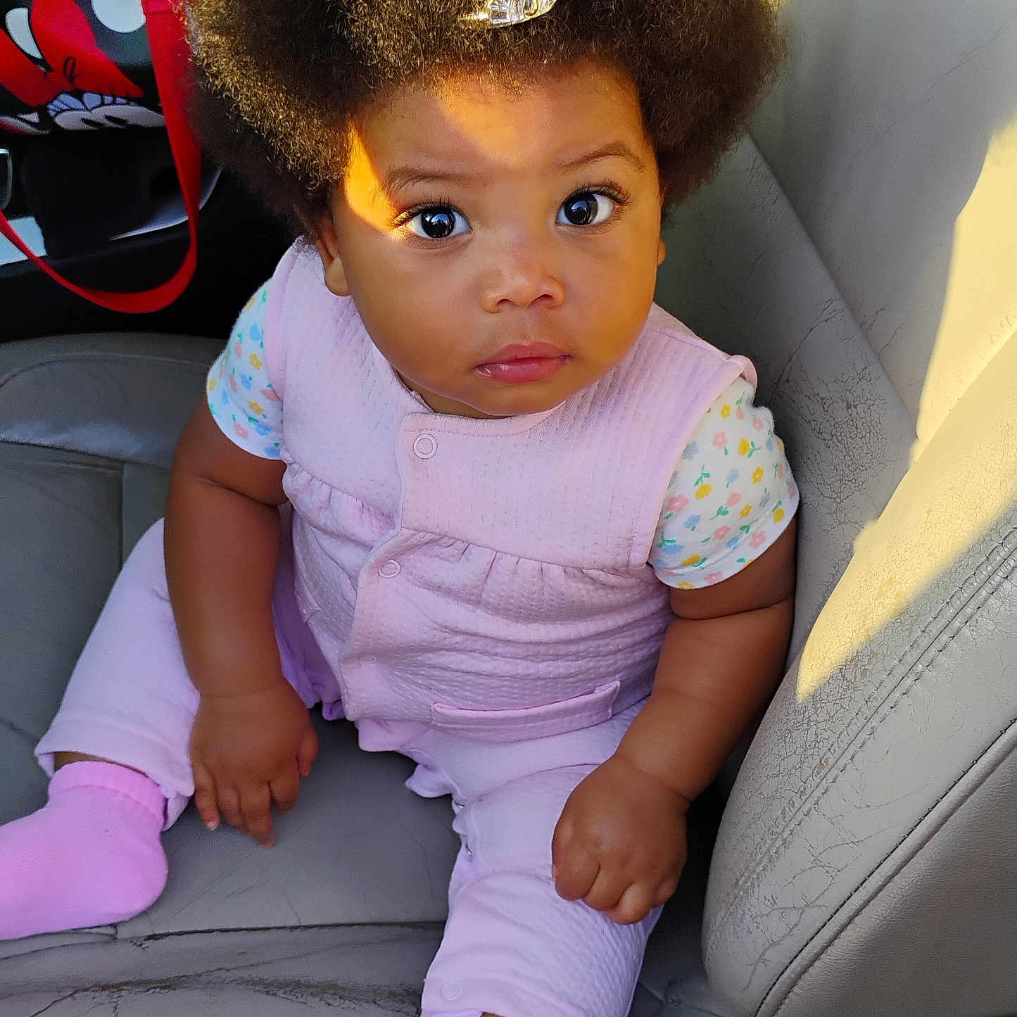 Ka'Miya joined the competition — help win amazing prizes! afro_hair, baby, car_seat, child, curious_expression, cute, hair_clip, hand, indoors, leather, patterned_shirt, person, pink_clothing, portrait, seat, short_sleeve, sitting, sock, sunlight, toddler