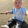 toddler, child, playground, stick, outdoor, sunlight, curious, blonde_hair, sitting, rubber_mulch, casual_clothing, bib, shoes, pants, long_sleeve_shirt, daylight, nature, play, young_child, cute