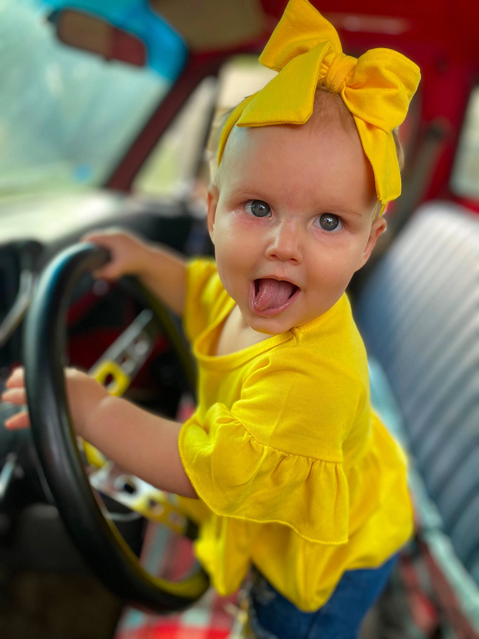 Megara is registered to the contest to win money with this photo: auto_part, baby, baby_products, child, costume_hat, event, family_car, fashion_accessory, fun, happy, hat, leisure, motor_vehicle, party_supply, person, recreation, smile, steering_wheel, surprise, toddler