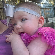 Emberley Hughes is registered to the contest to win money with this photo: baby, bow, child, closeup, curious, earrings, fabric, face, fence, hand, headband, outdoor, person, pink_dress, portrait, purple_shirt, resting, skin, sparkle, sunlight