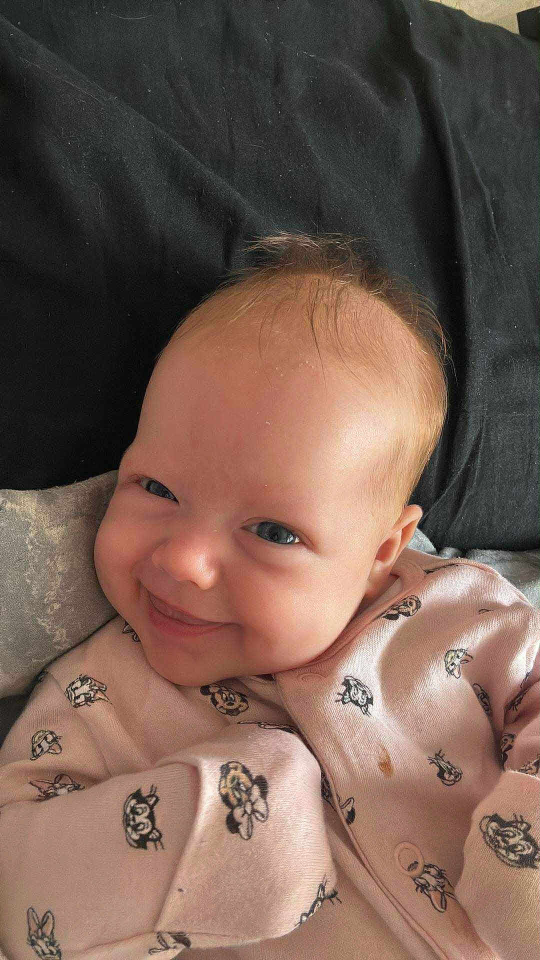 Maddison joined the competition — help win amazing prizes! baby, infant, smile, face, clothing, pink_outfit, cartoon_print, blanket, cute, child, portrait, happy, skin, head, lying_down, young_child, human, baby_clothes, soft, indoors