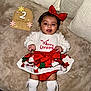 baby, blanket, celebration, child, christmas_outfit, clothing, couch, cute, festive, happy, holiday, indoors, infant, months_marker, portrait, red_bow, sitting, smiling, white_socks, wooden_sign
