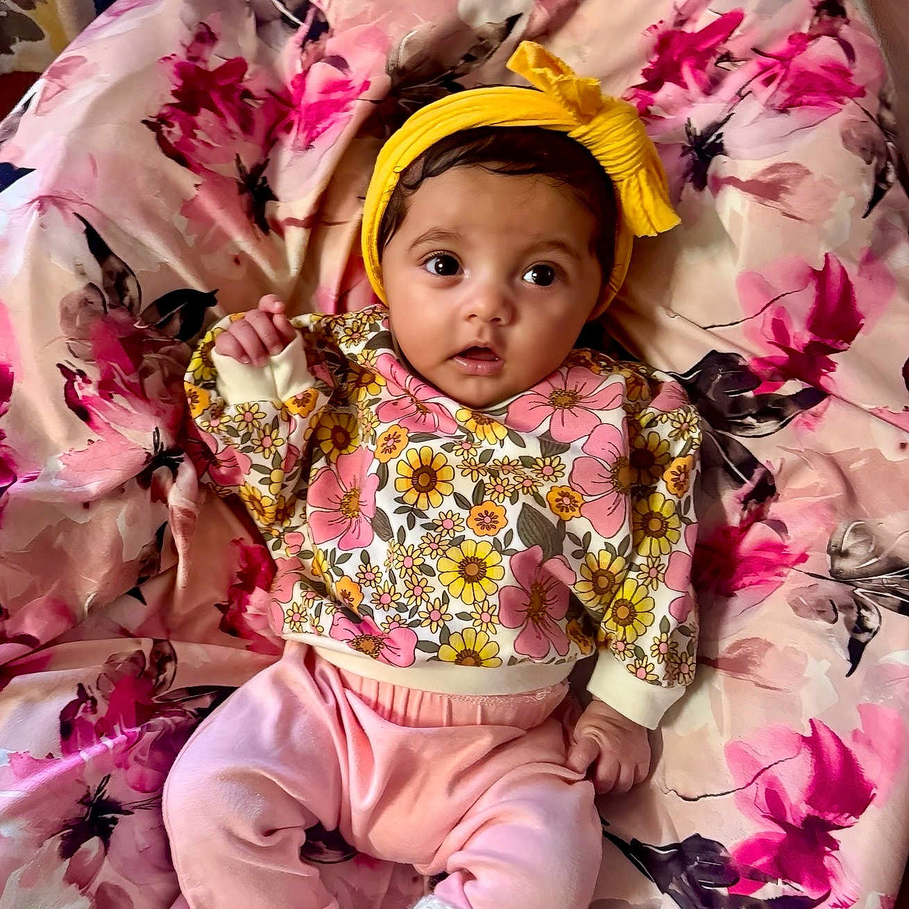 Azayla is registered to the contest to win money with this photo: adorable, baby, blanket, child, clothing, colorful, cute, expression, face, floral_pattern, indoors, infant, knitted_booties, lying_down, pink_pants, portrait, small_hand, soft_toys, yellow_headband, young