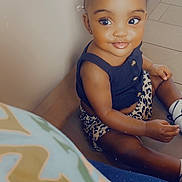 Aaliyah joined the competition — help win amazing prizes! toddler, child, smiling, sitting, indoor, pigtails, hair_bows, black_top, leopard_print, shorts, socks, shoes, floor, tile_floor, cute, portrait, happy, young_child, baby, person