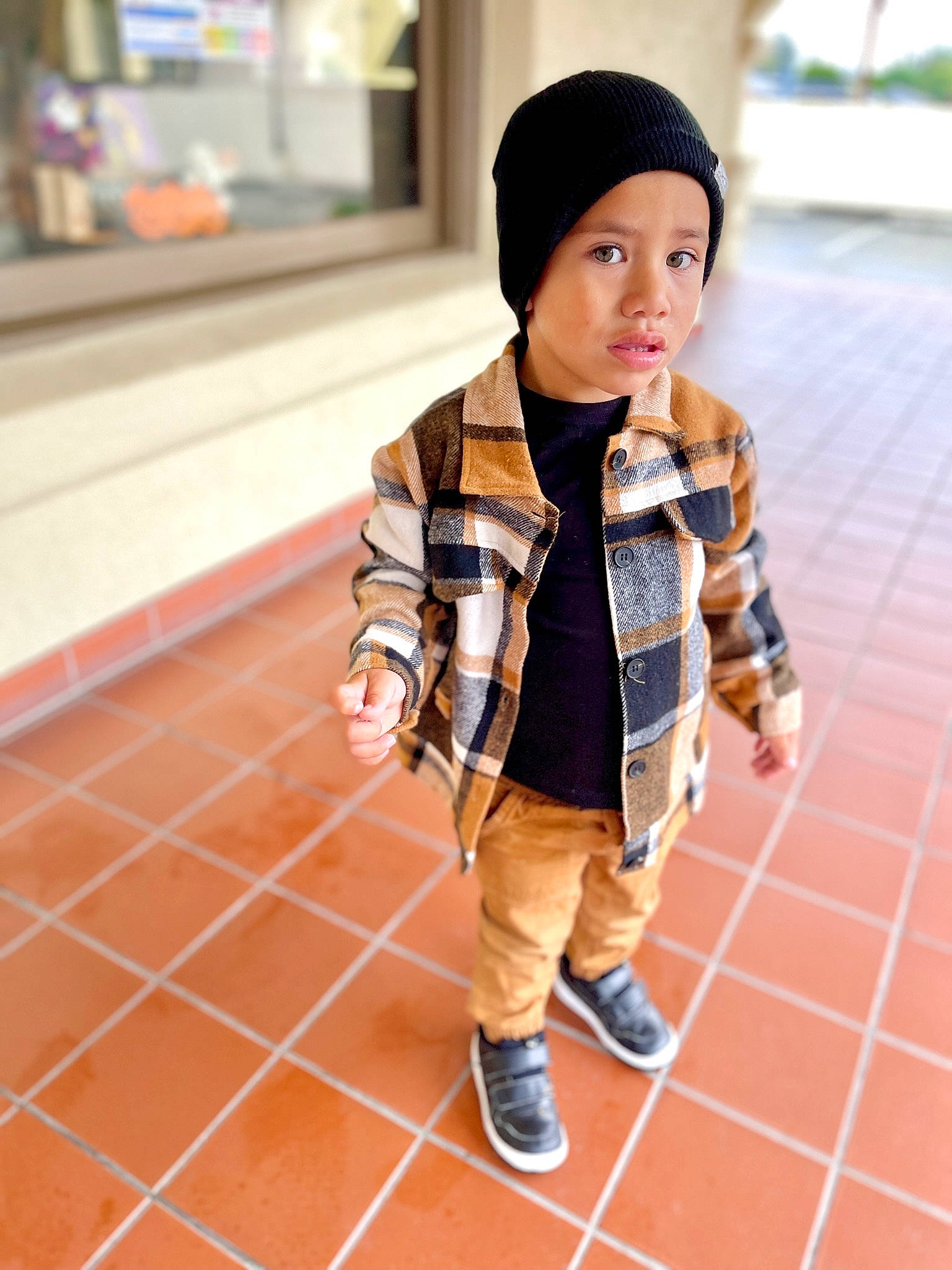 Isaiah is registered to the contest to win money with this photo: arm, cap, denim, finger, flooring, hand, headwear, human_leg, jacket, knee, luggage_and_bags, orange, pattern, person, plaid, shoe, sitting, sleeve, sneakers, thigh