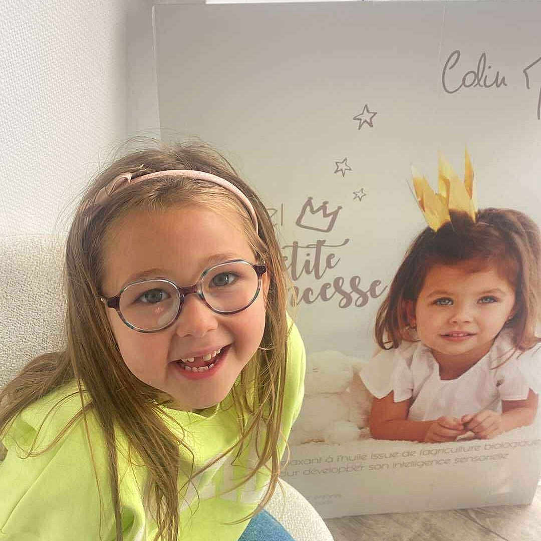 Adèlya participe au concours pour gagner de l'argent avec cette photo : chair, child, crown, floor, girl, glasses, happy, headband, indoor, jeans, portrait, poster, princess, sitting, smiling, text, wall, window_blinds, wooden_floor, yellow_sweater