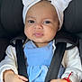 baby, blue_clothing, bow, car_seat, child, closeup, cute, face, hands, headband, indoors, infant, pacifier, portrait, red_bracelet, safety, seatbelt, smile, straps, white_cardigan