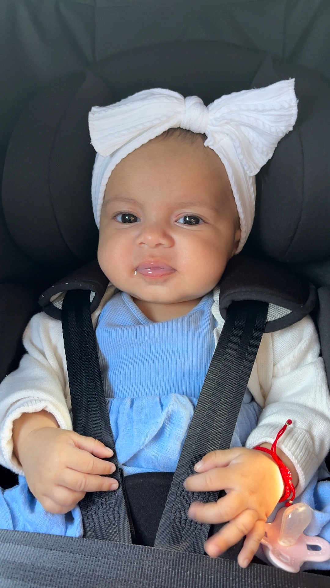 Alessia joined the competition — help win amazing prizes! baby, blue_clothing, bow, car_seat, child, closeup, cute, face, hands, headband, indoors, infant, pacifier, portrait, red_bracelet, safety, seatbelt, smile, straps, white_cardigan