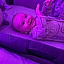 Lorenzo is registered to the contest to win money with this photo: baby, infant, smile, pajamas, bed, bedding, teddy_bear, purple_light, happy, child, face, hand, lying_down, indoor, cute, cozy, sleepwear, person, soft_toy, cheerful