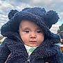 baby, child, hood, jacket, blue, face, outdoor, cloudy_sky, cute, eyes, person, hands, warm_clothing, infant, portrait, winter_wear, headwear, expression, soft_texture, closeup