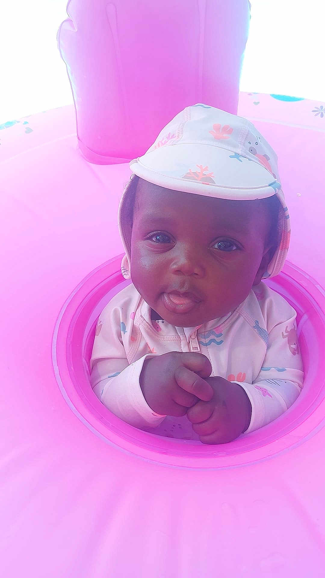 Psams-Marie joined the competition — help win amazing prizes! baby, child, infant, pink, inflatable, swim_ring, hat, clothing, face, hands, cute, water_toy, playful, summer, pool, outdoor, portrait, skin, expression, young