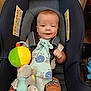 Kamron is registered to the contest to win money with this photo: baby, blanket, blue, car_seat, child, colorful, comfort, cute, fabric, face, happy, indoor, infant, orange_pants, patterned_clothing, plush_toy, seatbelt, smiling, toy, young