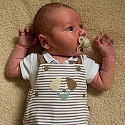 Elio participe au concours pour gagner de l'argent avec cette photo : baby, infant, pacifier, romper, striped_clothing, dog_applique, blanket, soft_texture, lying_down, curious, child, cute, indoors, skin, head, arm, hand, face, expression, clothing