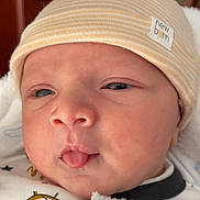 Daniel participe au concours pour gagner de l'argent avec cette photo : baby, newborn, infant, hat, blanket, face, tongue, closeup, expression, cute, child, sleepwear, striped, new_born_label, indoors, soft_light, portrait, wrapped, clothing, resting