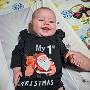 Lya participe au concours pour gagner de l'argent avec cette photo : baby, child, smiling, onesie, black_clothing, santa_claus, reindeer, christmas, hand_holding, toy, indoor, happy, cute, infant, face, person, festive, holiday, patterned_background, playful