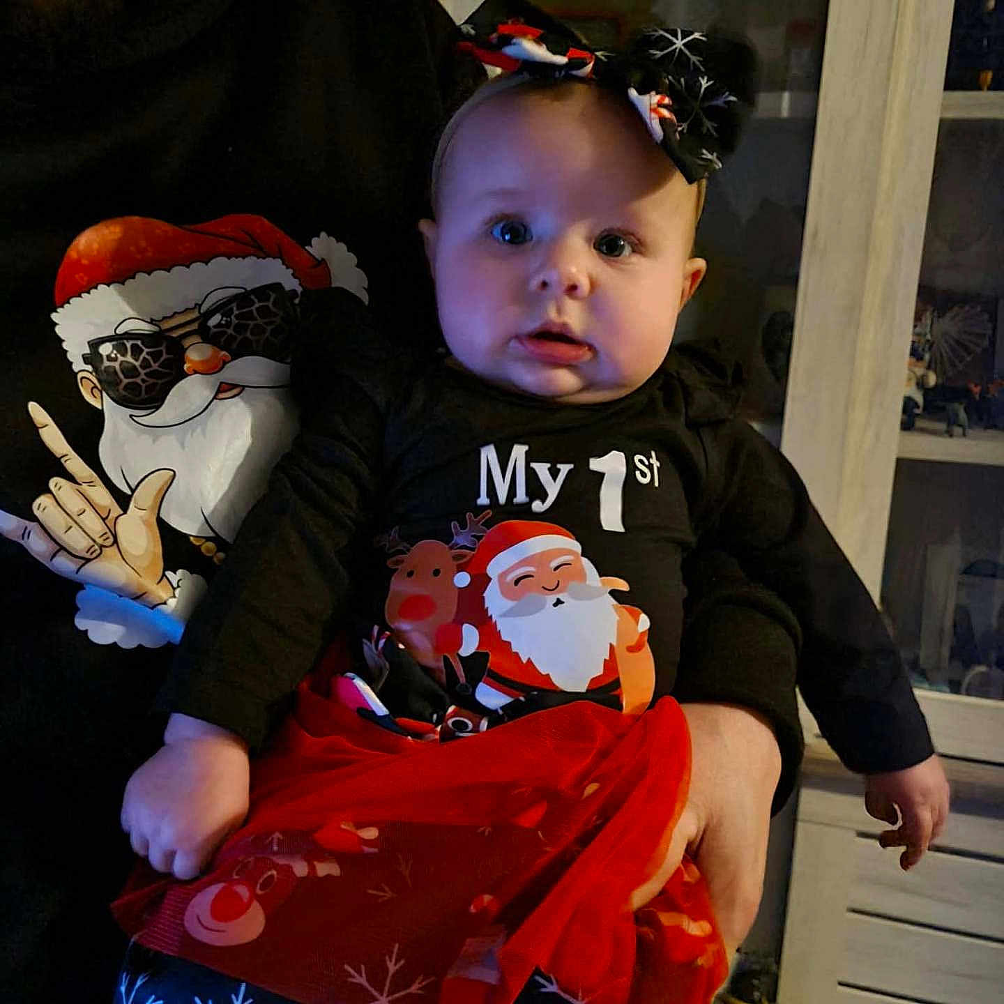 Lya a rejoint le concours — aidez-le/la à gagner de superbes lots ! adult, baby, black_clothing, bow, cabinet, child, christmas, decor, expression, face, festive_clothing, headband, holding, holiday, indoors, person, portrait, red_skirt, reindeer, snowflake_pattern