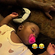 Tanya joined the competition — help win amazing prizes! adult_arm, baby, blanket, casual, child, controller, cute, emoji, funny, hand, indoors, infant, pacifier, patterned_fabric, pink, relaxed, resting, sleeping, sofa, video_game