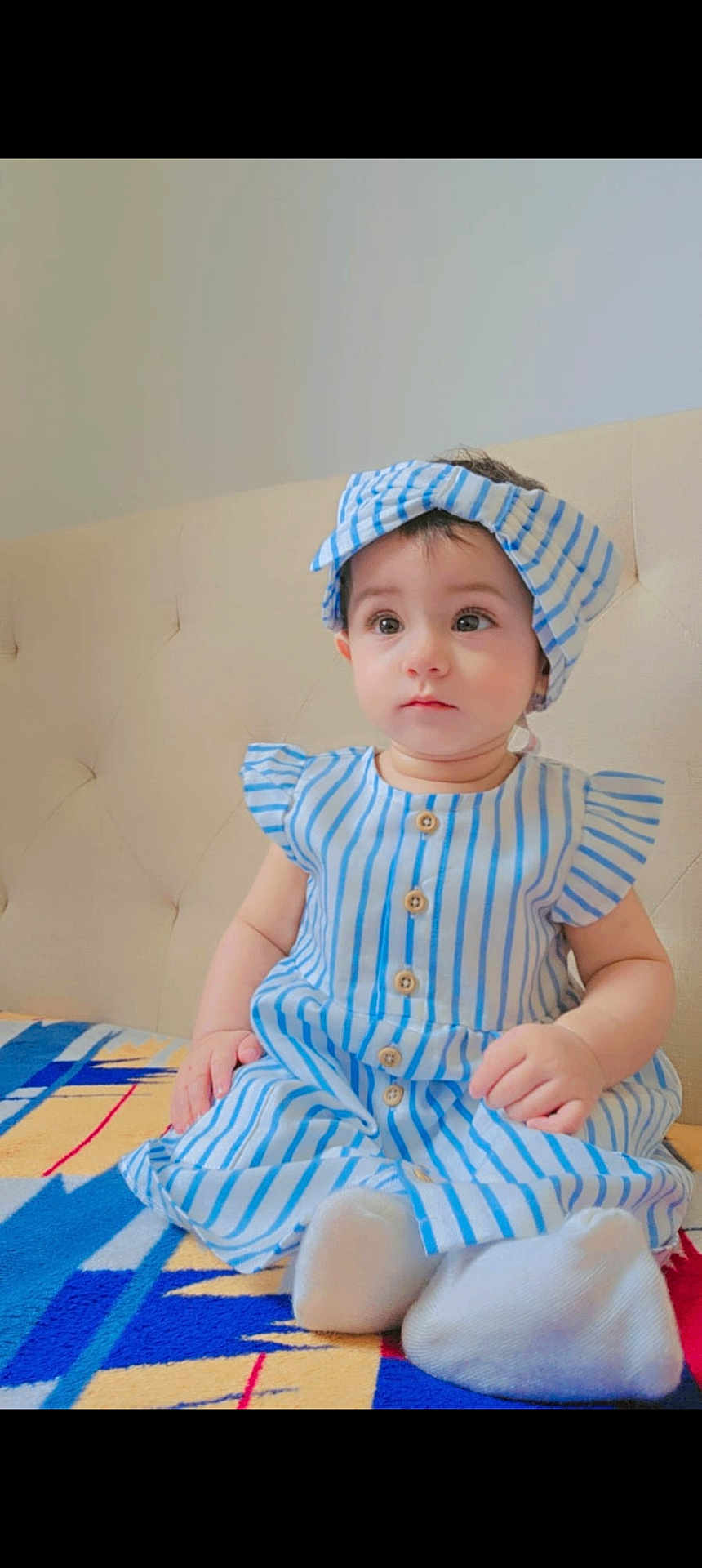 Minha joined the competition — help win amazing prizes! baby, child, girl, infant, sitting, blue_and_white_stripes, headband, dress, patterned_blanket, indoors, curious_expression, cute, small_hands, white_socks, soft_lighting, portrait, face, young, adorable, seated