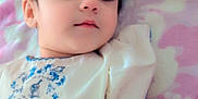 Minha is registered to the contest to win money with this photo: baby, blanket, child, closeup, clothing, cute, dress, face, hair, hand, indoors, infant, lying_down, pattern, person, portrait, skin, sleepy, soft_lighting, young_child