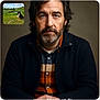 animal, beard, blue_sky, casual_clothing, clouds, dog, grass, head_and_shoulders, indoor, inset_photo, man, nature, neutral_background, outdoor, pet, photography, plaid_shirt, pond, portrait, serious_expression