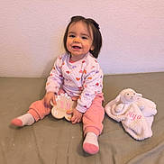 Aélya participe au concours pour gagner de l'argent avec cette photo : baby, child, infant, smiling, sitting, toy, plush, blanket, heart_pattern, pink_clothing, wooden_plaque, indoor, bed, cute, happy, female, young_child, portrait, cozy, soft_texture