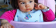 Aélya participe au concours pour gagner de l'argent avec cette photo : toddler, child, high_chair, bib, pink, indoor, face, expression, food, hand, hair, clothing, person, young_child, table, seat, cute, portrait, baby, skin