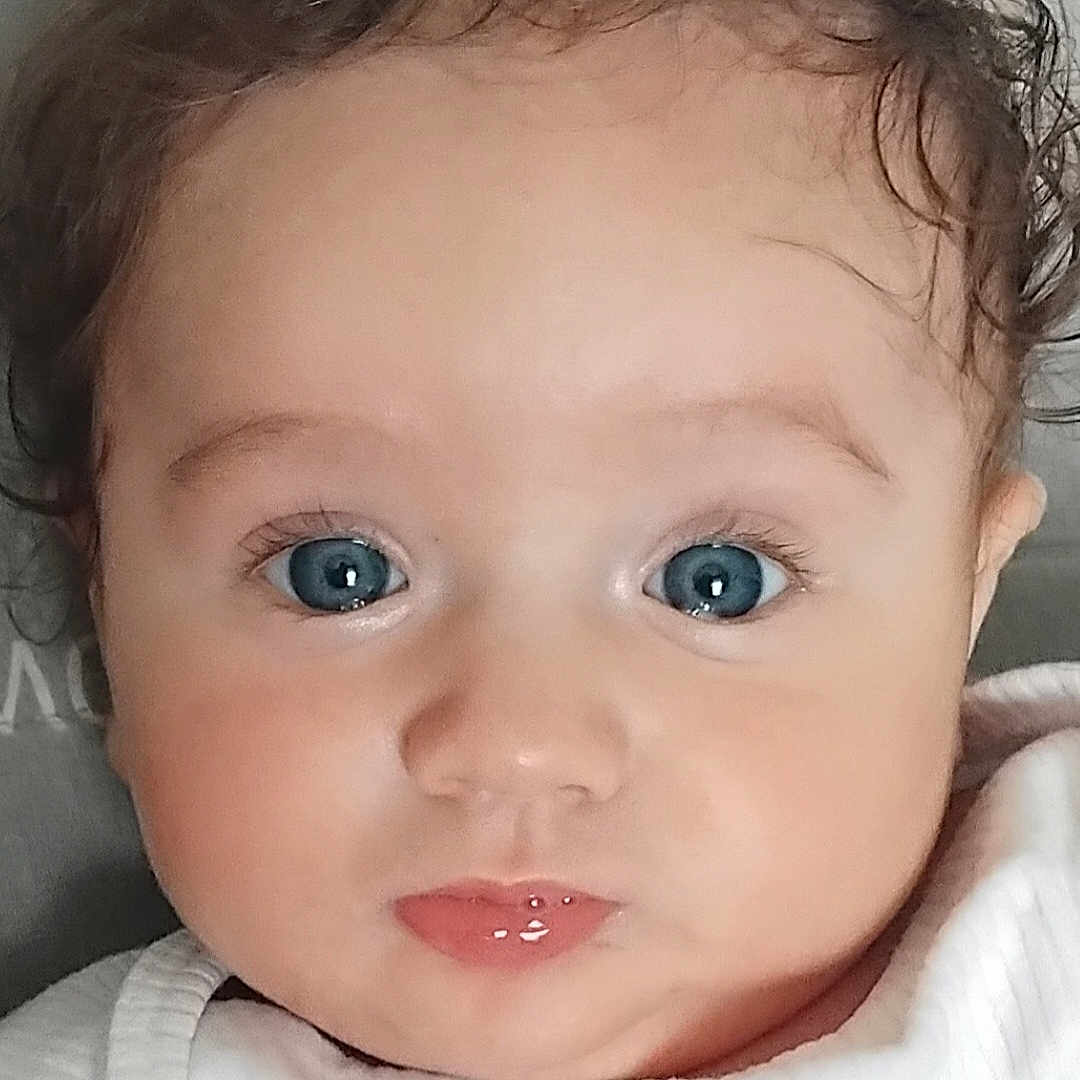 Lyham a rejoint le concours — aidez-le/la à gagner de superbes lots ! baby, infant, closeup, blue_eyes, curly_hair, face, cute, child, portrait, white_clothing, skin, expression, small_lips, young, person, head, indoors, soft_light, innocent, adorable