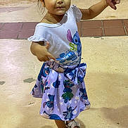 Arlenis joined the competition — help win amazing prizes! child, girl, standing, holding_hand, white_shirt, stitch_character, purple_skirt, sandals, outdoor, concrete_floor, tiles, short_hair, smiling, cute, fashion, young, person, footwear, hand, casual