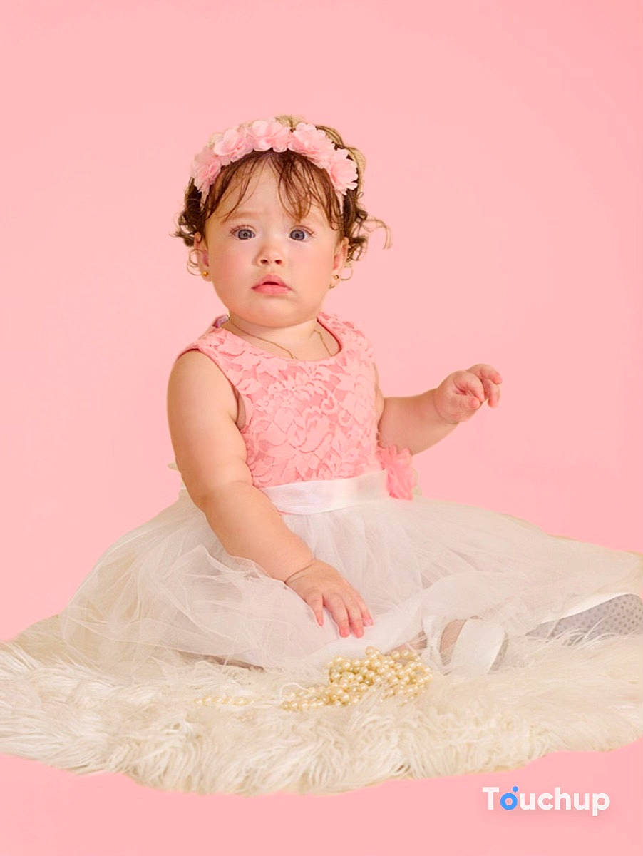 Allison is registered to the contest to win money with this photo: arm, baby, baby_toddler_clothing, child, day_dress, dress, embellishment, face, fashion_accessory, hair_accessory, happy, headpiece, magenta, pattern, peach, person, pink, ruffle, sitting, sleeve