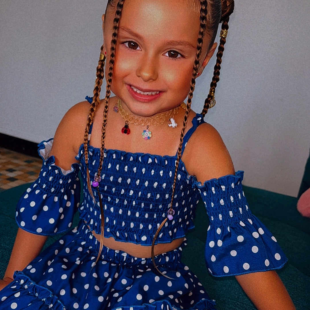 Jade a rejoint le concours — aidez-le/la à gagner de superbes lots ! accessories, blue_dress, braids, casual, child, colorful, couch, cute, fashion, girl, hair_buns, happy, indoor, necklace, person, polka_dot, portrait, sitting, smiling, young