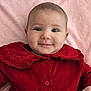 baby, child, face, smile, red_dress, velvet, infant, portrait, cute, lying_down, pink_blanket, happy, young_child, clothing, button, collar, skin, head, eyes, hand