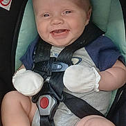 Ashtyn is registered to the contest to win money with this photo: baby, infant, car_seat, mittens, smiling, happy, child, safety_harness, cute, foot, clothing, seatbelt, person, indoors, closeup, face, head, plush, comfort, rest