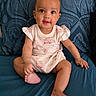 baby, blue_bed, bright_eyes, child, clothing, cute, expression, face, feet, hands, indoors, infant, onesie, pattern, person, pillow, portrait, sitting, skin, smile