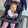 baby, canopy, child, cup_holder, floral_shirt, happy, harness, parking_lot, pavement, pigtails, pink_pants, plush_toy, pram, seat, shoes, smile, sneakers, stroller, sunlight, toddler