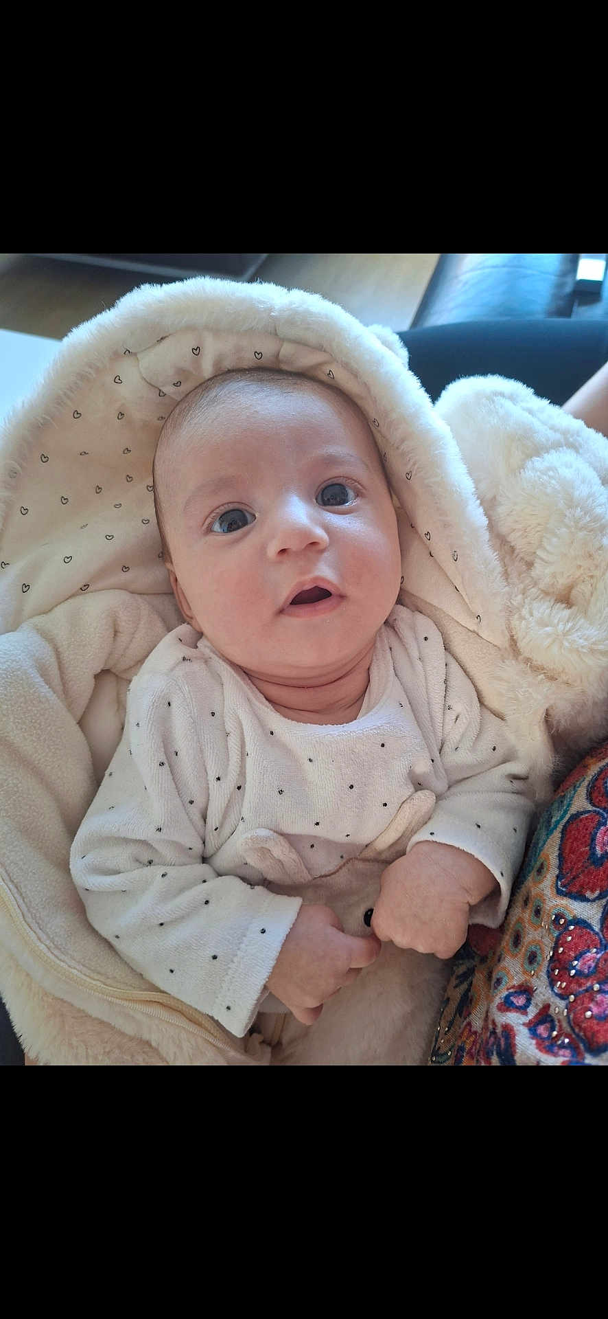 Elisa-Lina participe au concours pour gagner de l'argent avec cette photo : baby, infant, blanket, hood, cozy, soft_toy, hand, face, expression, clothing, patterned_fabric, curious, wide_eyes, indoor, cute, child, portrait, warm, newborn, fuzzy