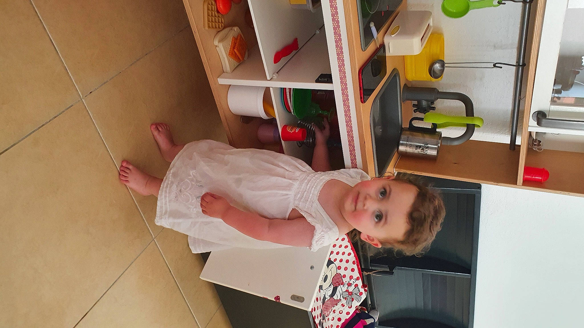 Malya a rejoint le concours — aidez-le/la à gagner de superbes lots ! baby_toddler_clothing, bookcase, child, dress, flooring, happy, house, human_leg, person, room, shelf, shelving, smile, toddler, wheel, wood