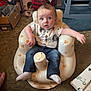 baby, child, infant, person, inflatable_chair, teddy_bear_pattern, jeans, shirt, socks, hair, mohawk, carpet, room, foot, box, furniture, plastic, curious, expression, indoor