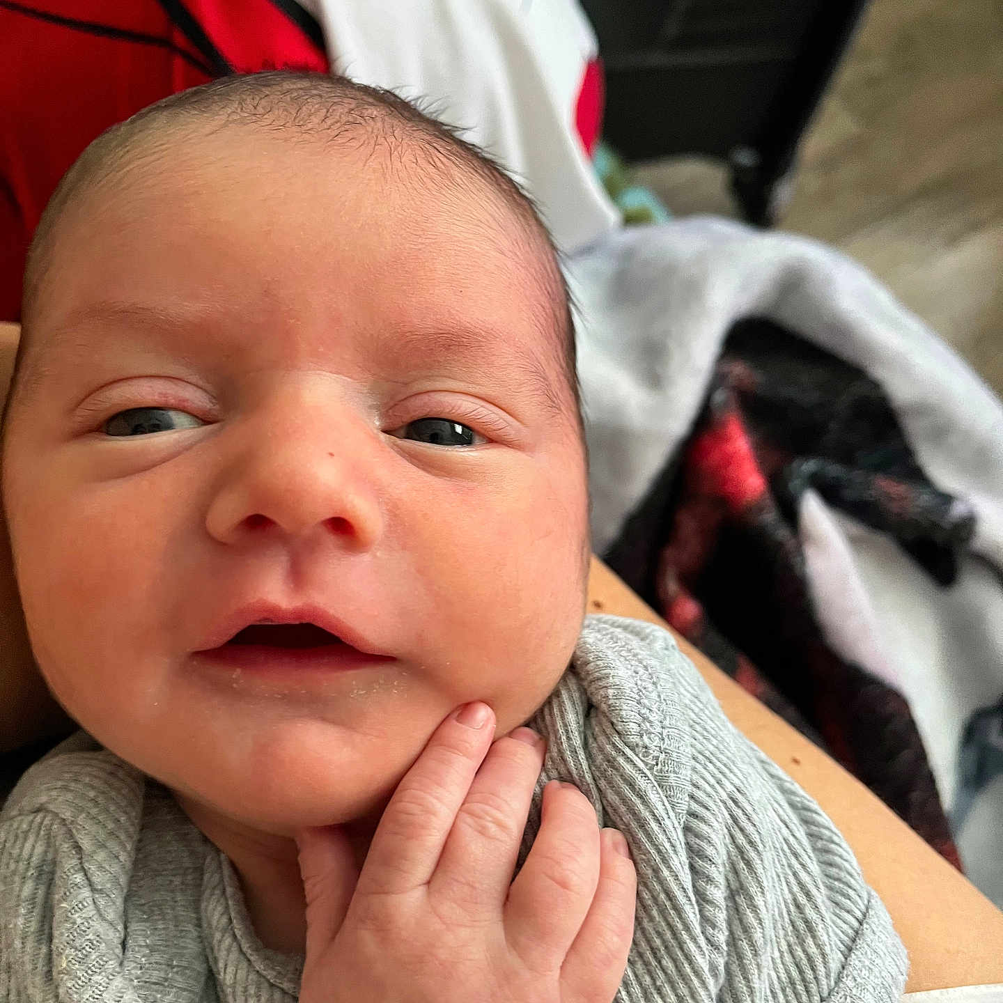 Asher joined the competition — help win amazing prizes! newborn, baby, infant, child, face, portrait, wide_eyed, awake, cozy, gray_clothing, onesie, adult_hand, supporting_hand, blanket, car_seat, close_up, indoor, candid, skin, family